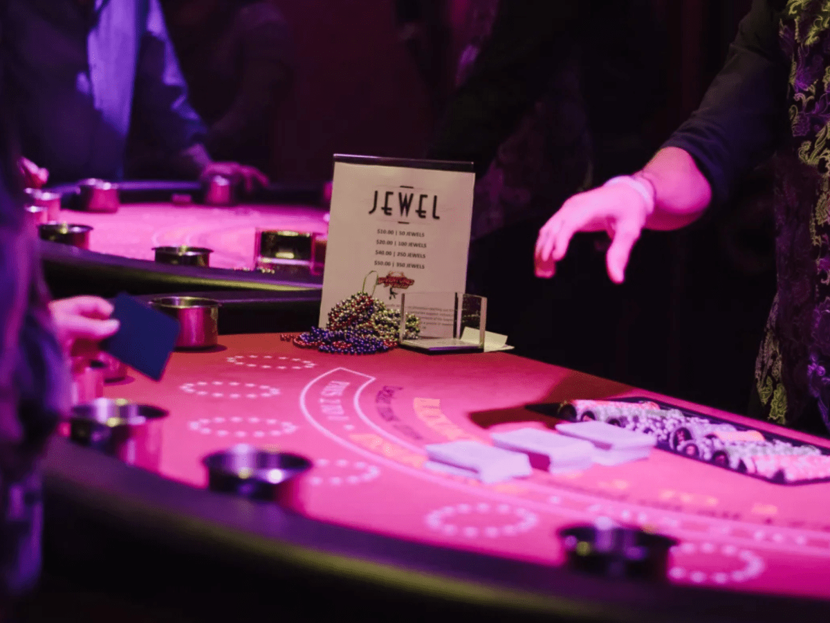 People at a casino table with chips and a sign reading 'Jewel'.