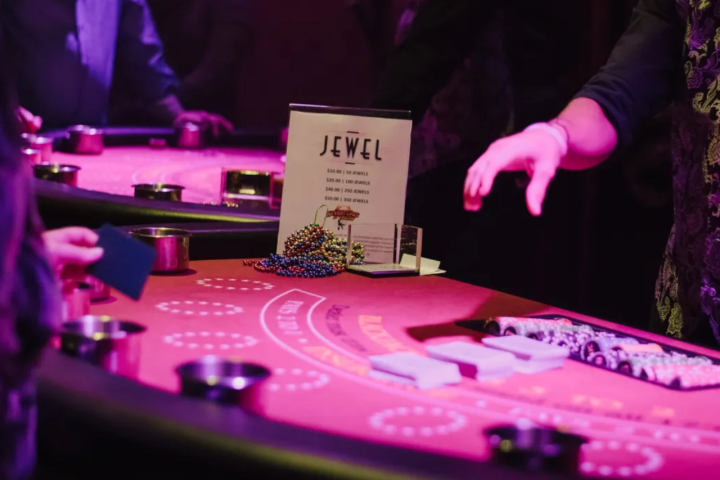 People at a casino table with chips and a sign reading 'Jewel'.