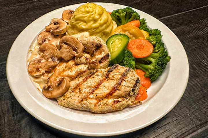 Grilled chicken with mushrooms, mashed potatoes, and mixed vegetables on a plate.