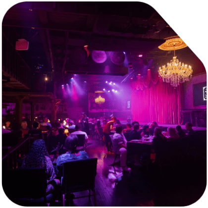 Dimly lit restaurant with chandeliers, red drapes, and seated guests.