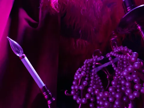 Pink light bulb, beads, and feather with a magenta glow.
