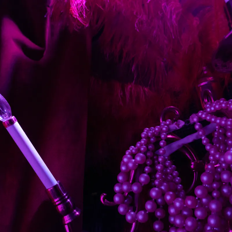 Pink light bulb, beads, and feather with a magenta glow.