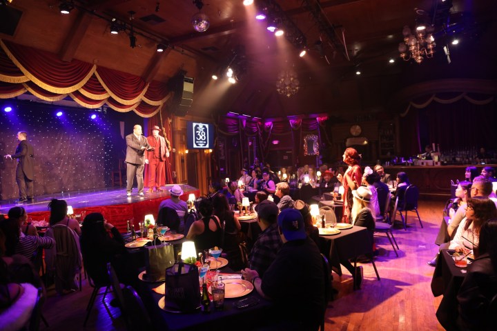Cabaret show with performers on stage and audience seated at tables.